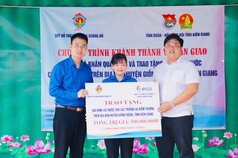 A representative of the Red Scarf House Support Fund presents a symbolic plaque for the donation of 500 water purifiers to the Giong Rieng District Youth Union